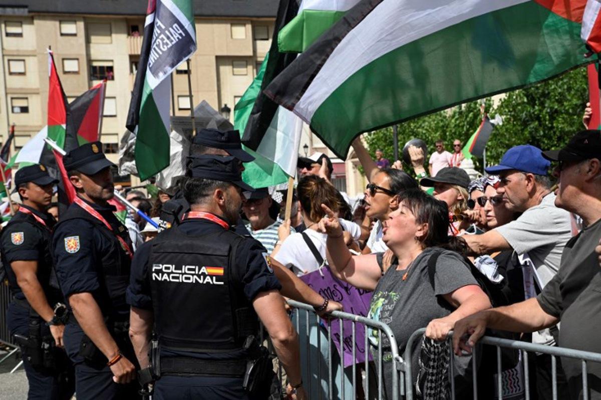 Pro-Palestinian protesters confront police as they wave flags at the start of the 15th stage of the Vuelta a Espana cycling tour, a 167 km race between A Veiga/Vegadeo and Monforte de Lemos, on September 7, 2025. Miguel RIOPA / AFP