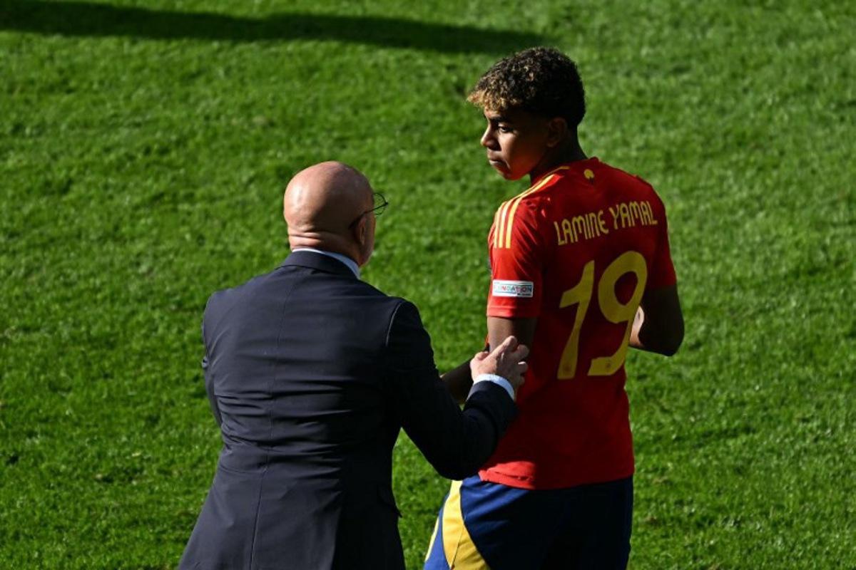 Spain's head coach Luis de la Fuente speaks with Spain's forward #19 Lamine Yamal during the UEFA Euro 2024 Group B football match between Spain and Croatia at the Olympiastadion in Berlin on June 15, 2024. GABRIEL BOUYS / AFP