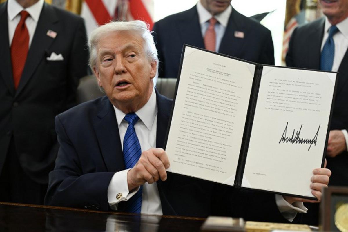 US President Donald Trump holds up a signed executive order in the Oval Office in the White House in Washington, DC, on January 30, 2026. ANNABELLE GORDON / AFP