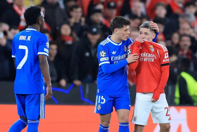 SL Benfica's Argentine forward #25 Gianluca Prestianni hides his mouth while arguing with Real Madrid's Brazilian forward #07 Vinicius Junior who complained about alleged racists insults during the UEFA Champions League knockout round play-off first leg football match between SL Benfica and Real Madrid CF at Estadio da Luz in Lisbon on February 17, 2026. PATRICIA DE MELO MOREIRA / AFP