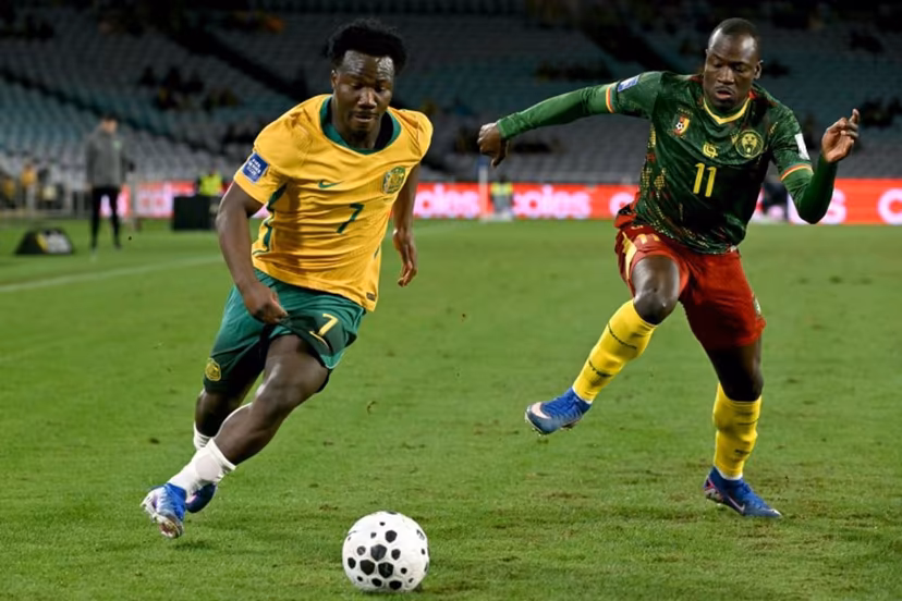 Australia's Nestory Irankunda (L) runs with the ball past Cameroon's Saidou Alioum Moubarak (R) during the international friendly football match between Australia and Cameroon at Stadium Australia in Sydney on March 27, 2026. SAEED KHAN / AFP