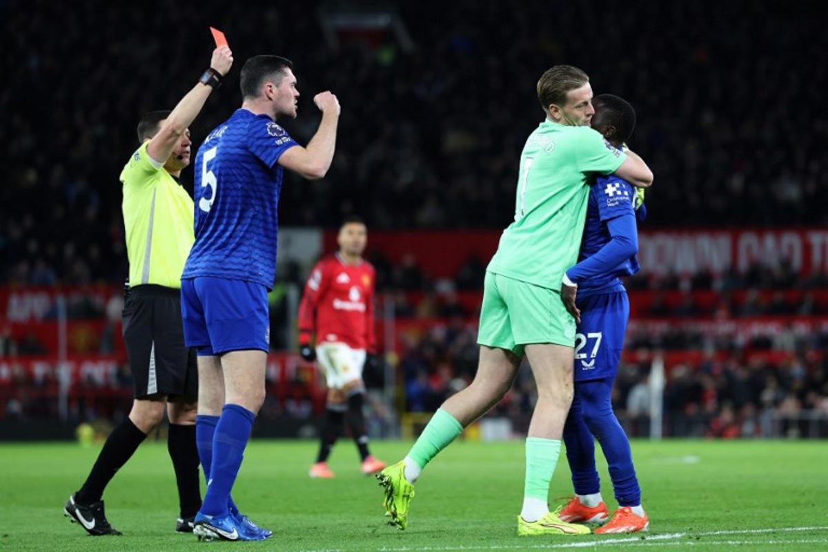 Everton's English goalkeeper #01 Jordan Pickford (2R) separates Everton's Senegalese midfielder #27 Idrissa Gueye (R) from Everton's English defender #05 Michael Keane (2L) as English referee Tony Harrington (L) shows a red card to Gueye during the English Premier League football match between Manchester United and Everton at Old Trafford in Manchester, north west England, on November 24, 2025. Darren Staples / AFP
