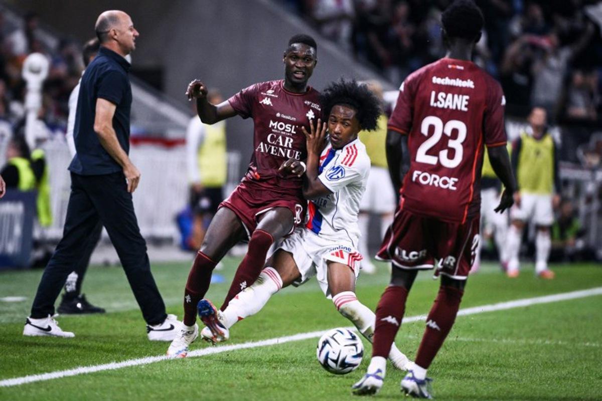 Lyon's Belgian forward #11 Malick Fofana (C) fights for the ball with Metz's Malian midfielder #08 Boubacar Traore (L) during the French L1 football match between Olympique Lyonnais (OL) and FC Metz at the Groupama Stadium in Decines-Charpieu, central-eastern France on August 23, 2025. ARNAUD FINISTRE / AFP