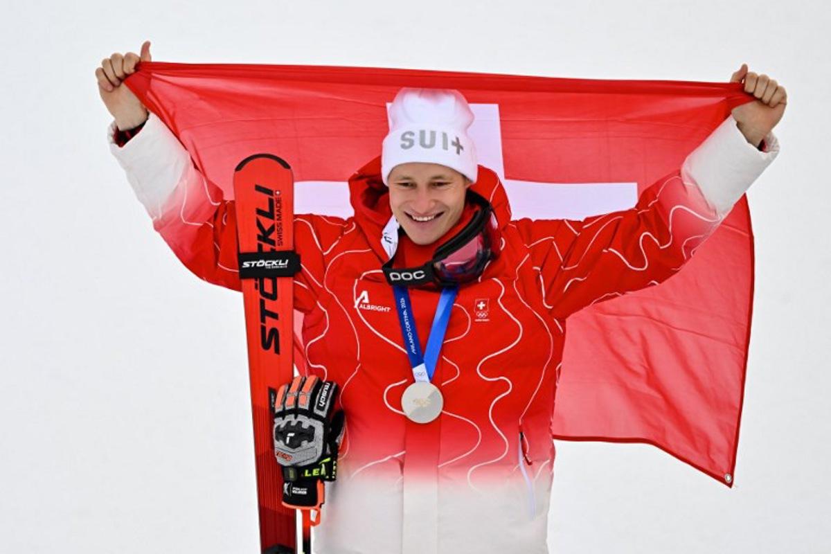 Switzerland's silver medalist Marco Odermatt holds up a Swiss flag after the men's giant slalom alpine skiing event during the Milano Cortina 2026 Winter Olympic Games at the Stelvio Ski Centre in Bormio (Valtellina) on February 14, 2026. Fabrice COFFRINI / AFP