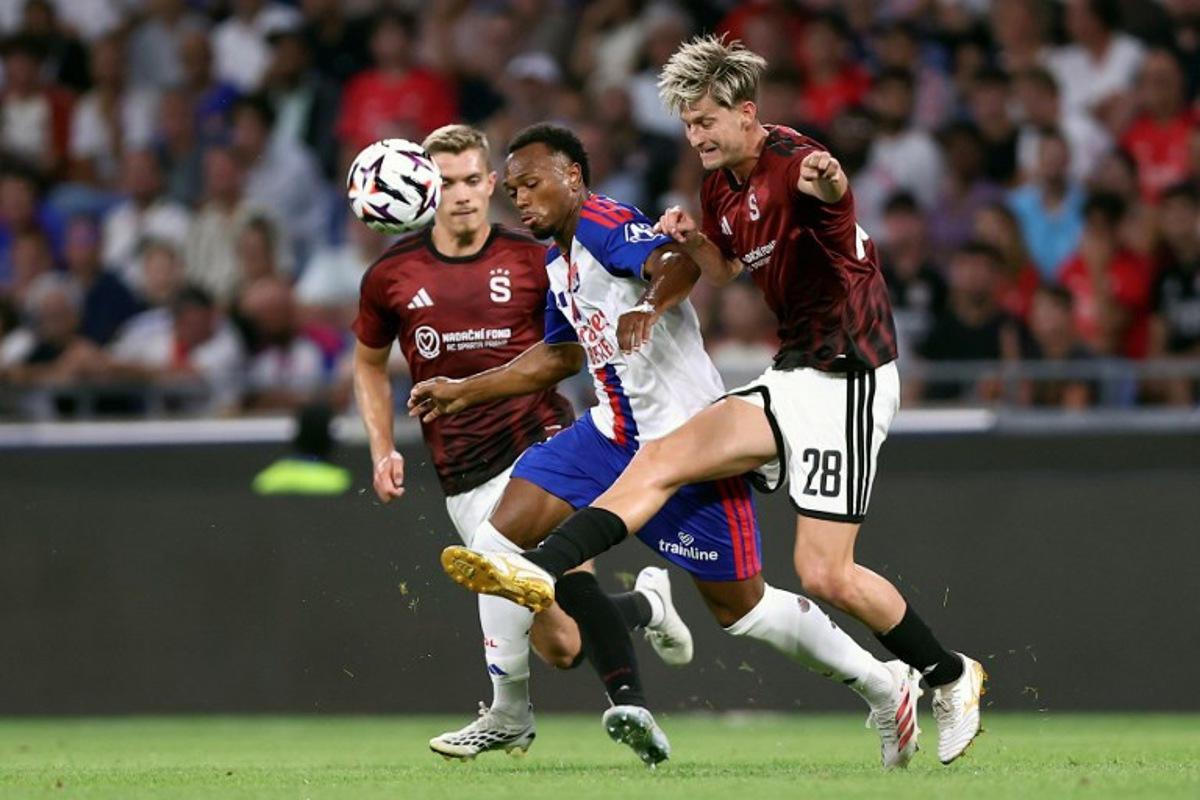 Lyon's Belgian forward #17 LoÏs Openda (C) fights for the ball with Sparta Praha's Czech midfielder #28 Roman Macek (R) during the UEFA Champions League third qualifying round - second leg football match between Olympique Lyonnais (OL) and Sparta Prague at Groupama Stadium in Decines-Charpieu, central-eastern France on August 11, 2026. Alex MARTIN / AFP