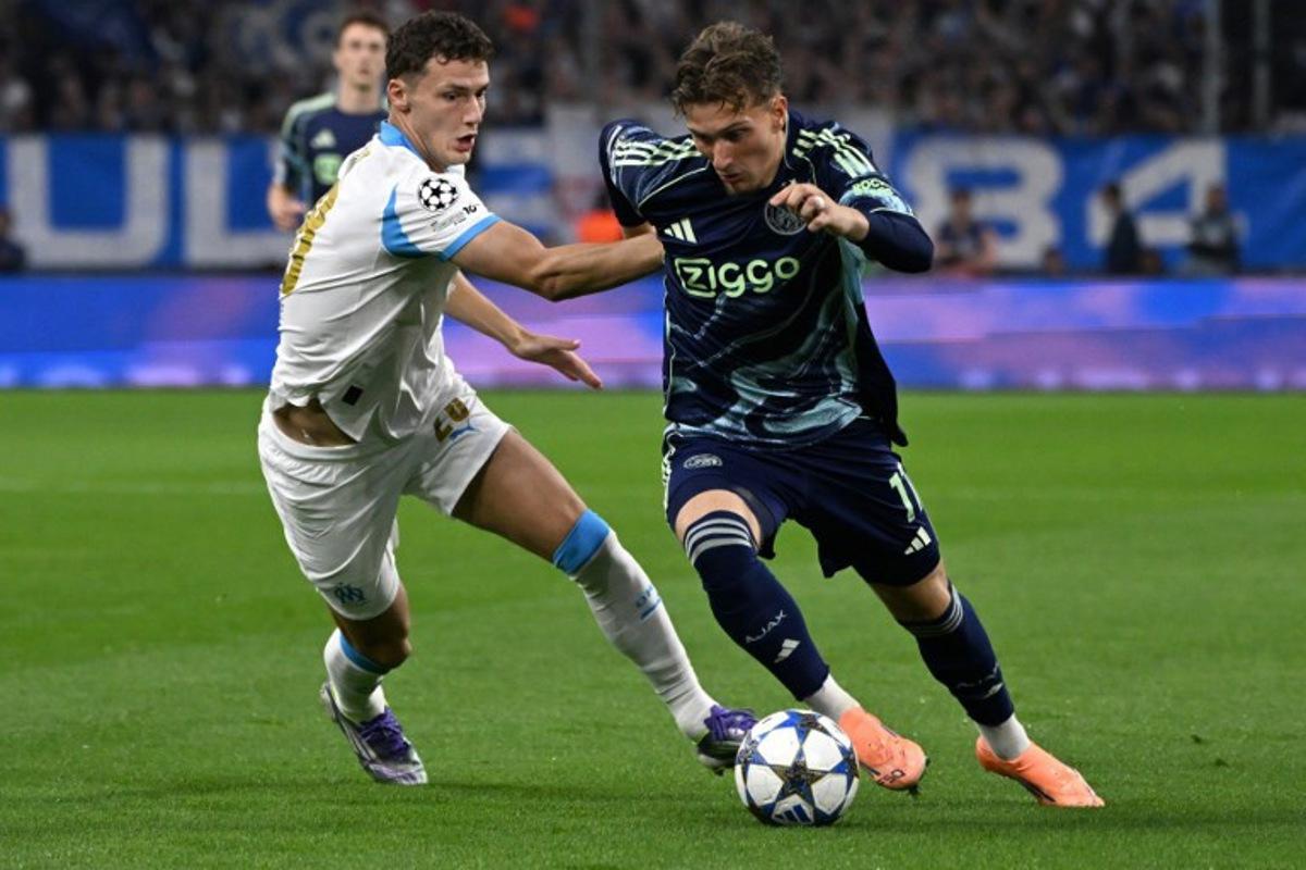 Marseille's French defender #28 Benjamin Pavard (L) and Ajax's Belgian forward #11 Mika Godts fight for the ball during the UEFA Champions League, league phase day 2, football match between Olympique de Marseille (FRA) and AFC Ajax (NED) at the Velodrome stadium, in Marseille on September 30, 2025. Miguel MEDINA / AFP