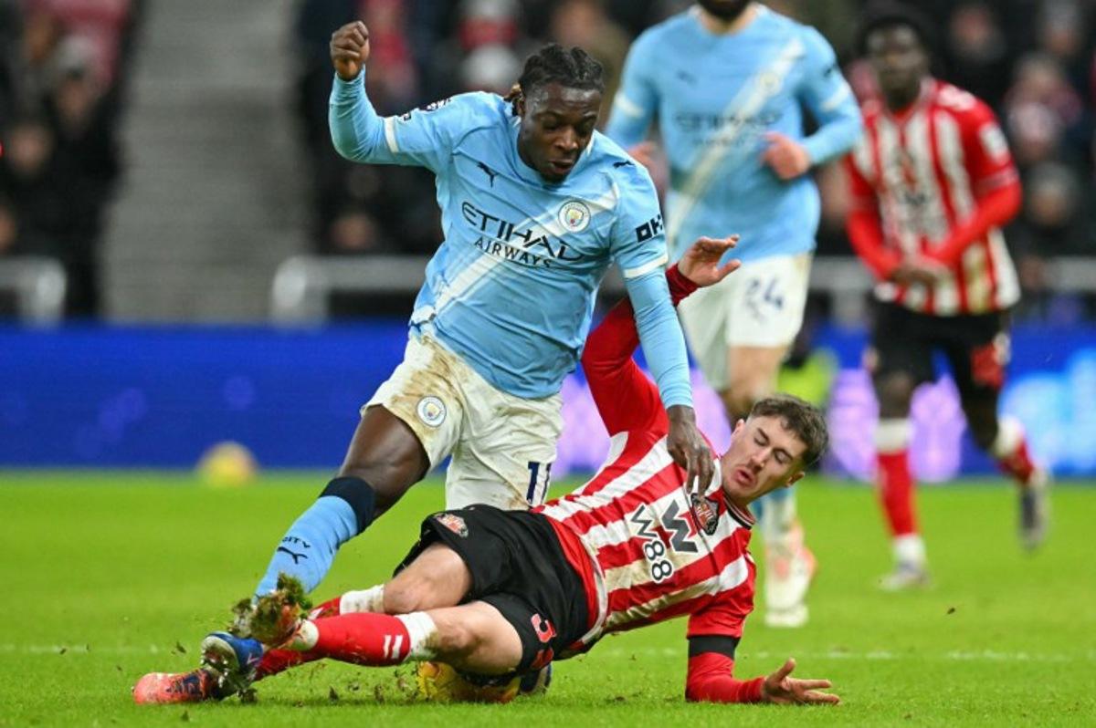 Sunderland's Northern Irish defender #32 Trai Hume (R) slides in to foul Manchester City's Belgian midfielder #11 Jeremy Doku (L) during the English Premier League football match between Sunderland and Manchester City at The Stadium of Light in Sunderland in north east England on January 1, 2026. ANDY BUCHANAN / AFP
