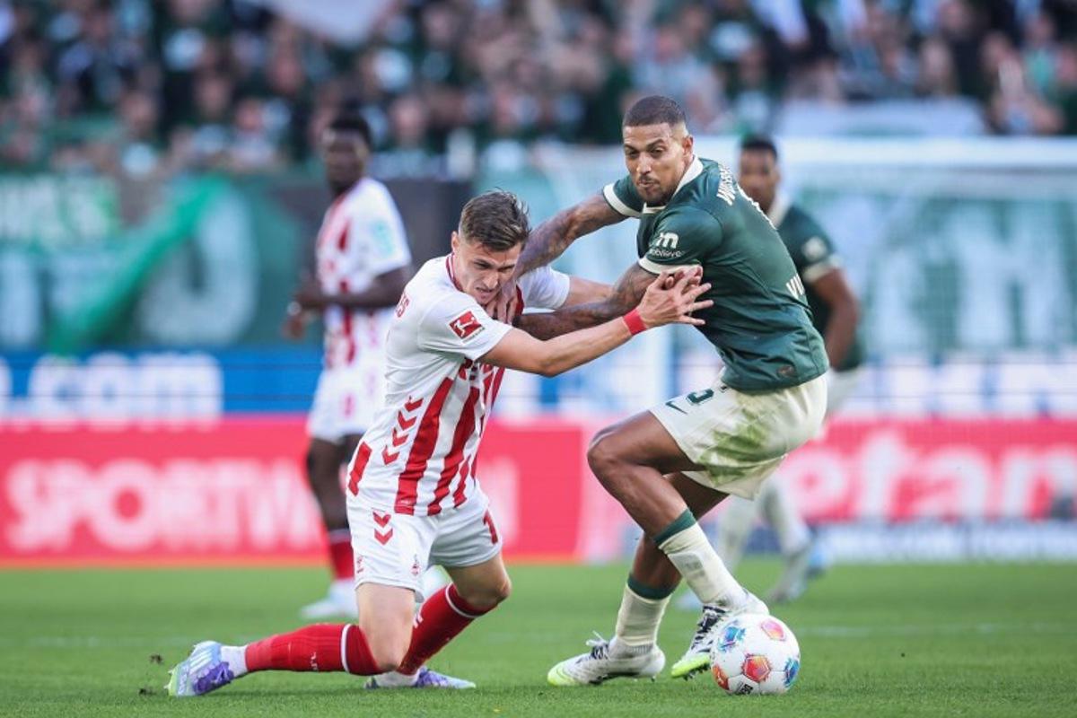Wolfsburg's Brazilian midfielder #05 Vinicius Souza (R) and FC Cologne's Belgian-Spanish midfielder #17 Alessio Castro-Montes vie for the ball during the German first division Bundesliga football match between VfL Wolfsburg and FC Cologne in Wolfsburg, northern Germany, on September 13, 2025. Ronny Hartmann / AFP