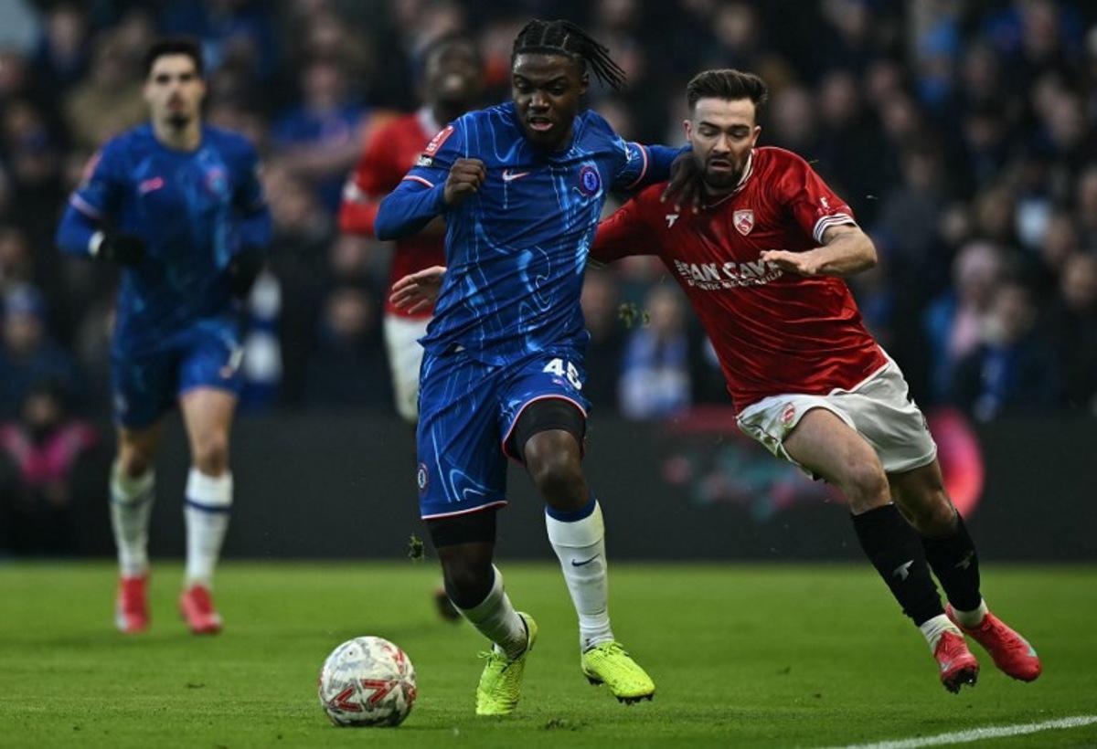 Morecambe's Welsh midfielder #07 Gwion Edwards (R) fouls Chelsea's Belgian midfielder #45 Romeo Lavia during the English FA Cup third round football match between Chelsea and Morecambe at Stamford Bridge in London on January 11, 2025. Ben STANSALL / AFP