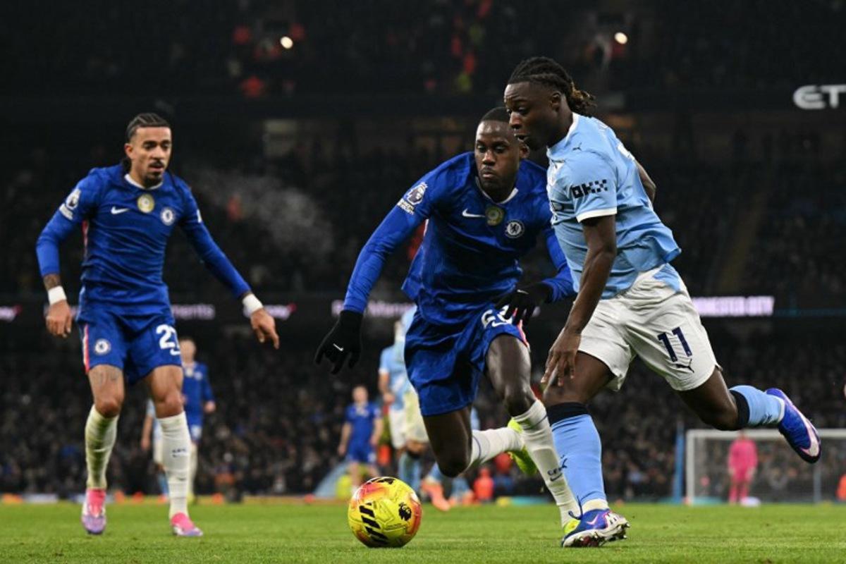Manchester City's Belgian midfielder #11 Jeremy Doku (R) vies with Chelsea's English defender #23 Trevoh Chalobah (C) during the English Premier League football match between Manchester City and Chelsea at the Etihad Stadium in Manchester, north west England, on January 4, 2026. Oli SCARFF / AFP
