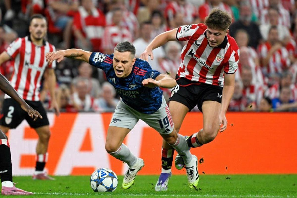 Arsenal's Belgian forward #19 Leandro Trossard falls as he fights for the ball with Athletic Bilbao's Spanish midfielder #18 Mikel Jauregizar Alboniga during the UEFA Champions League first round day 1 football match between Athletic Club Bilbao and Arsenal at the San Mames stadium in Bilbao on September 16, 2025. ANDER GILLENEA / AFP