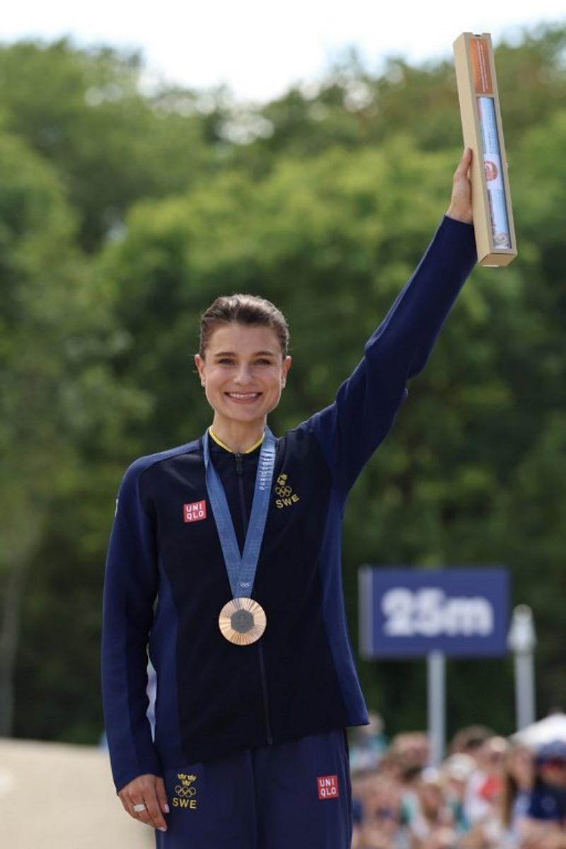 Bronze medallist Sweden's Jenny Rissveds celebrates on the podium after taking third place the women's cross-country mountain biking event during the Paris 2024 Olympic Games in Elancourt Hill venue in Elancourt, on July 28, 2024. Emmanuel DUNAND / AFP