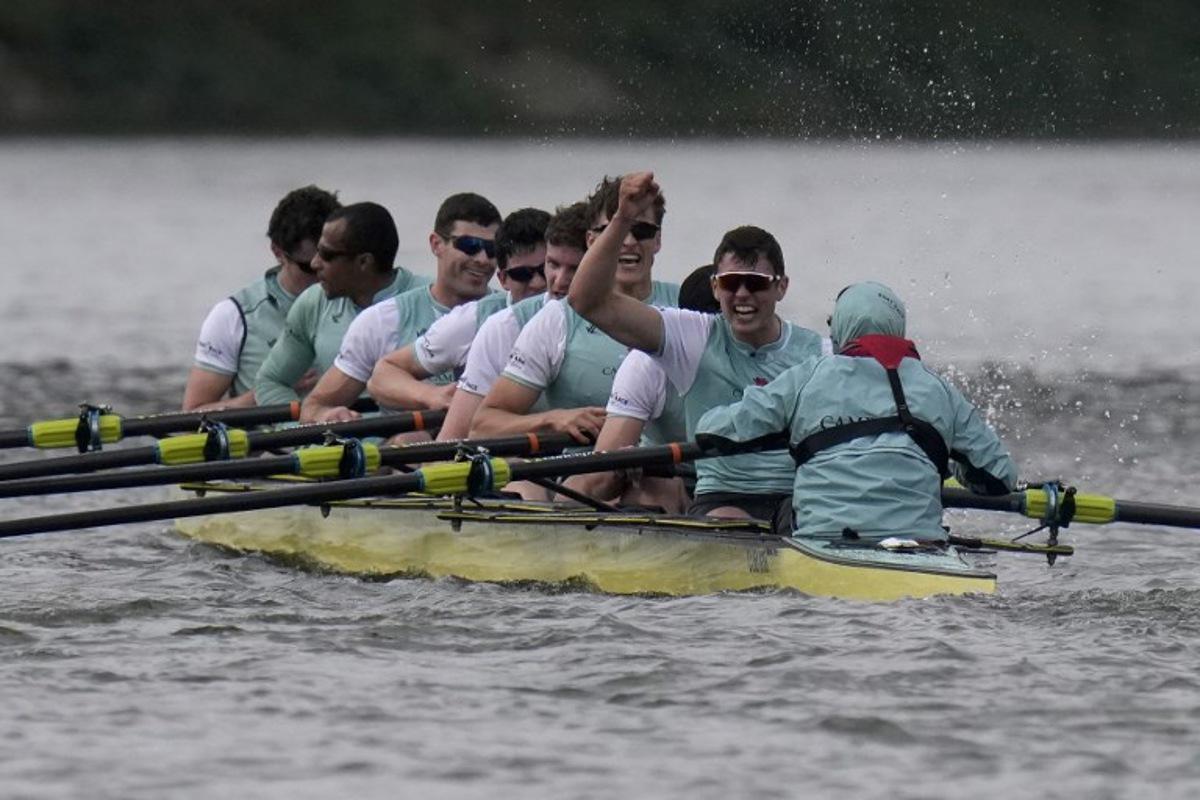 (R-L) Cambridge's Cox, Sammy Houdagui and rowers Freddy Breuer, Will Klipstine, Lexi McClean, Gabriel Obholzer, Patrick Wild, Kyle Fram, French president, Noam Mouelle, and Simon Hatcher celebrate winning the 171th men's boat race between Oxford University and Cambridge University on the River Thames in London on April 4, 2026. CARLOS JASSO / AFP