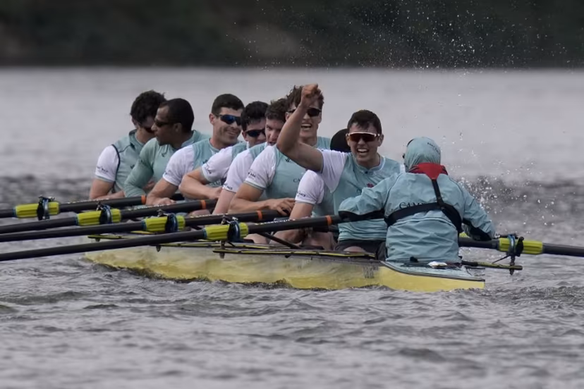(R-L) Cambridge's Cox, Sammy Houdagui and rowers Freddy Breuer, Will Klipstine, Lexi McClean, Gabriel Obholzer, Patrick Wild, Kyle Fram, French president, Noam Mouelle, and Simon Hatcher celebrate winning the 171th men's boat race between Oxford University and Cambridge University on the River Thames in London on April 4, 2026. CARLOS JASSO / AFP