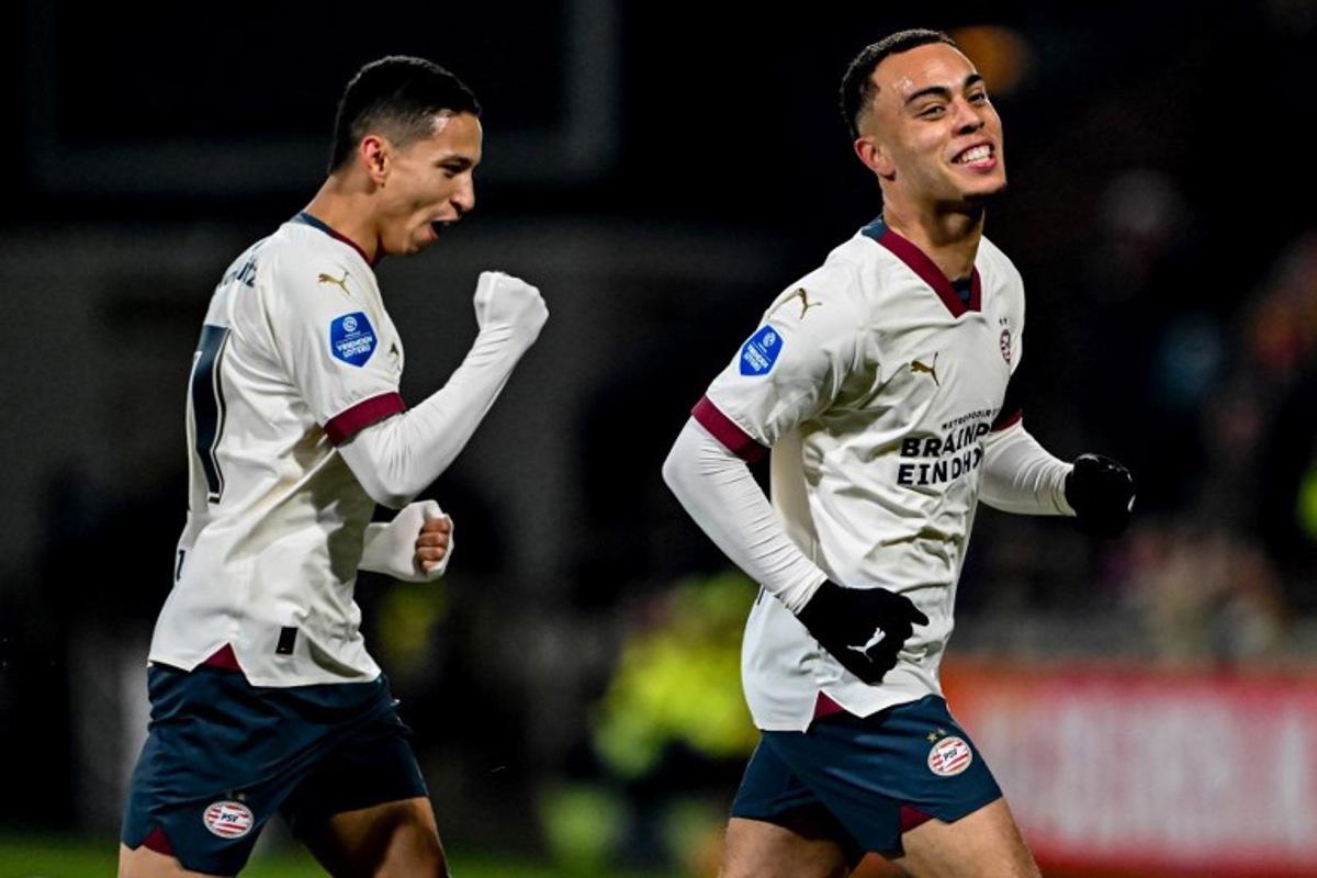 PSV's US midfielder #08 Sergino Dest (R) celebrates scoring his team's first goal with teammate PSV's Brazilian defender #17 Mauro Junior (L) during the Dutch Eredivisie football match between Go Ahead Eagles and PSV Eindhoven at De Adelaarshorst stadium in Deventer on March 8, 2024. Gerrit van Keulen / ANP / AFP
