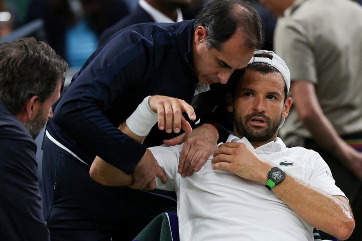Bulgaria's Grigor Dimitrov reacts as he receives medical treatment after getting injured as he plays against Italy's Jannik Sinner during their men's singles fourth round tennis match on the eighth day of the 2025 Wimbledon Championships at The All England Lawn Tennis and Croquet Club in Wimbledon, southwest London, on July 7, 2025. Adrian Dennis / AFP