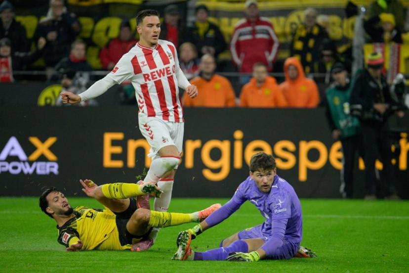 FC Cologne's German midfielder #13 Said El Mala (C) is tackled by Dortmund's Algerian defender #05 Ramy Bensebaini (L) in front of Dortmund's Swiss goalkeeper #01 Gregor Kobel's goal during the German first division Bundesliga football match between BVB Borussia Dortmund and 1 FC Cologne in Dortmund, Germany on October 25, 2025. Sascha Schuermann / AFP