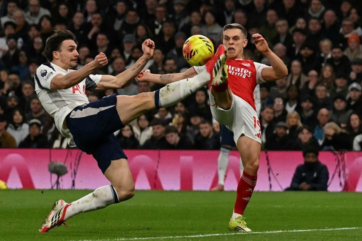 Arsenal's Belgian midfielder #19 Leandro Trossard (R) clashes with Tottenham Hotspur's Portugese midfielder #06 Joao Palhinha (L) during the English Premier League football match between Tottenham Hotspur and Arsenal at the Tottenham Hotspur Stadium in London, on February 22, 2026. Glyn KIRK / AFP
