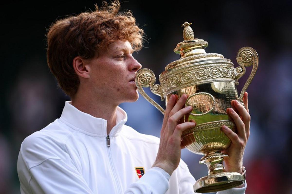 Italy's Jannik Sinner kisses the winner's trophy as he poses for pictures following his victory against Spain's Carlos Alcaraz at the end of their men's singles final tennis match on the fourteenth day of the 2025 Wimbledon Championships at The All England Lawn Tennis and Croquet Club in Wimbledon, southwest London, on July 13, 2025. HENRY NICHOLLS / AFP
