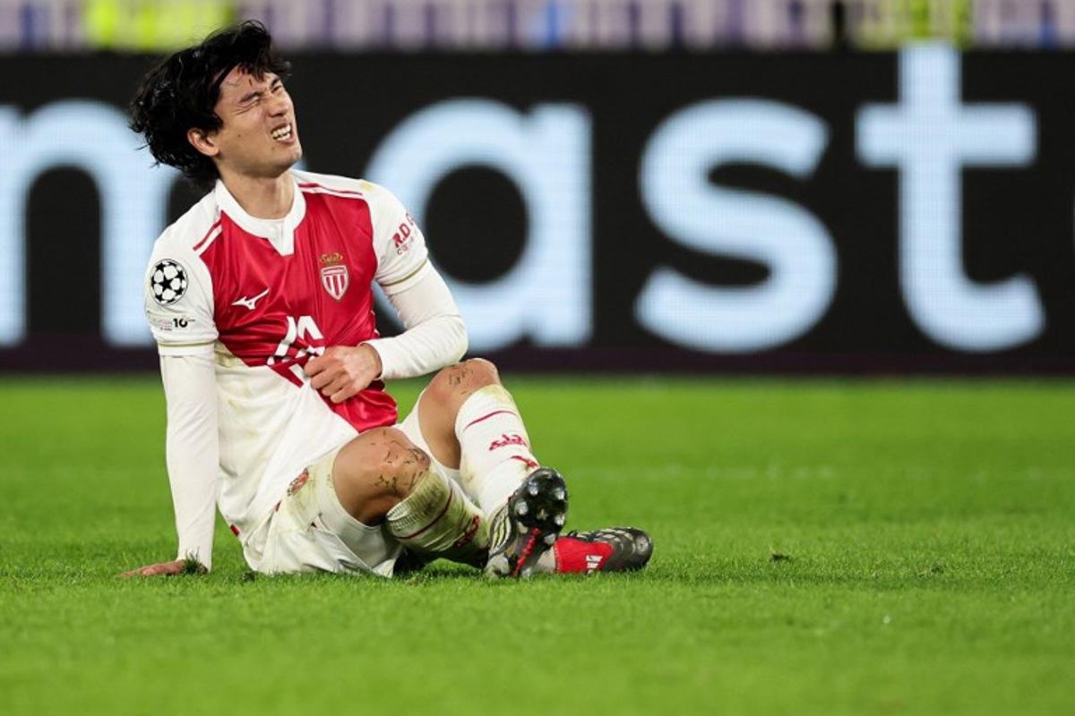 Monaco's Japanese forward #18 Takumi Minamino reacts after colliding with Galatasaray's Hungarian forward #07 Roland Sallai (unseen) during the UEFA Champions League, league phase, football match between Monaco and Galatasaray, at the Stade Louis II stadium, in Monaco, on December 9, 2025. Valery HACHE / AFP