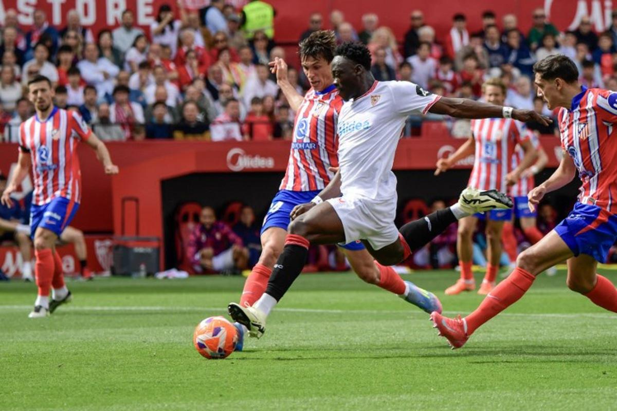 Sevilla's Nigerian forward #15 Akor Adams (C) is challenged by Atletico Madrid's Spanish defender #24 Robin Le Normand (L)during the Spanish league football match between Sevilla FC and Club Atletico de Madrid at the Ramon Sanchez Pizjuan stadium in Seville on April 6, 2025. CRISTINA QUICLER / AFP