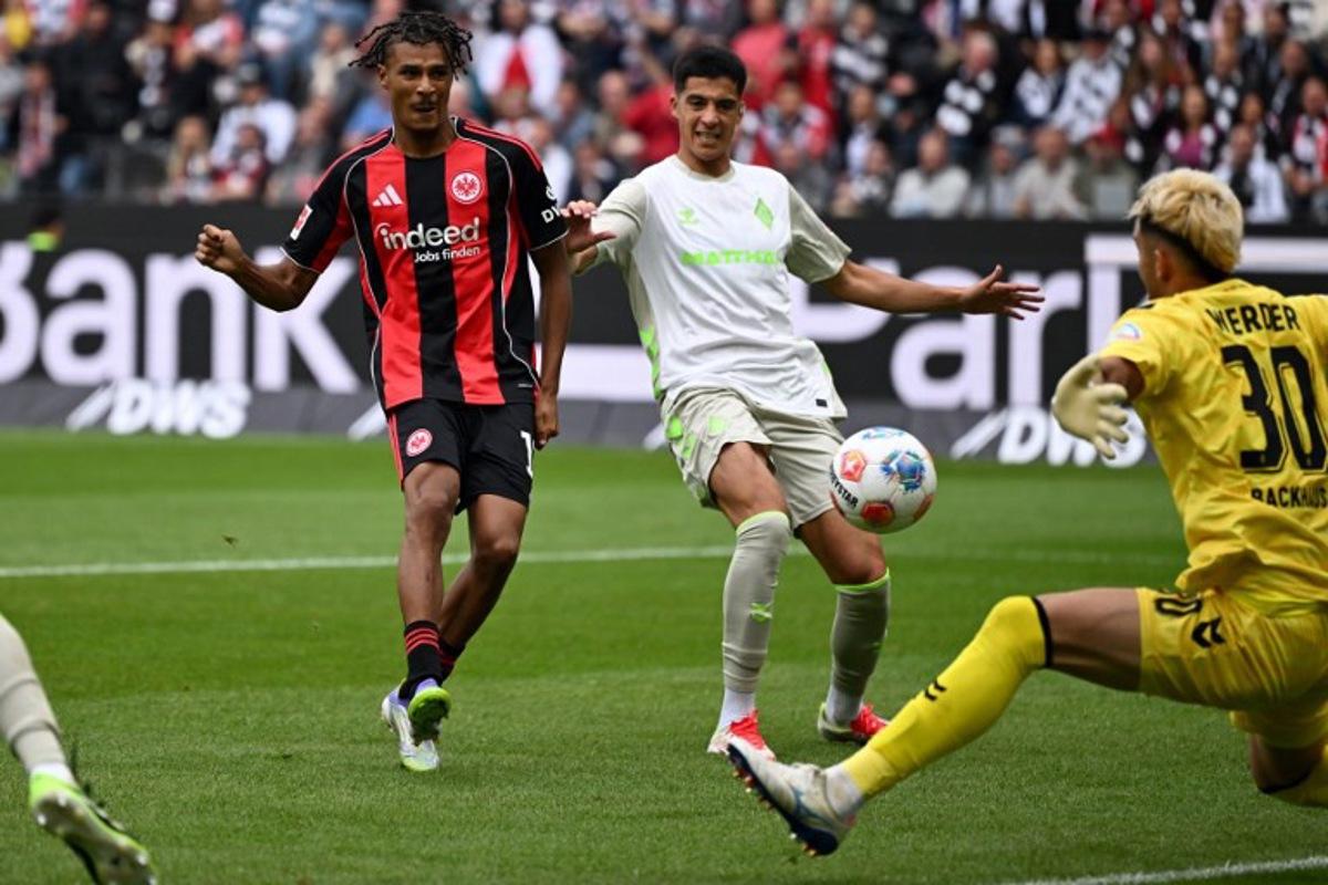 Frankfurt's French forward #19 Jean-Matteo Bahoya (L) scores his team's third goal past Bremen's German goalkeeper #30 Mio Backhaus (R) during the German first division Bundesliga football match between Eintracht Frankfurt and Werder Bremen in Frankfurt am Main, western Germany on August 23, 2025. Kirill KUDRYAVTSEV / AFP