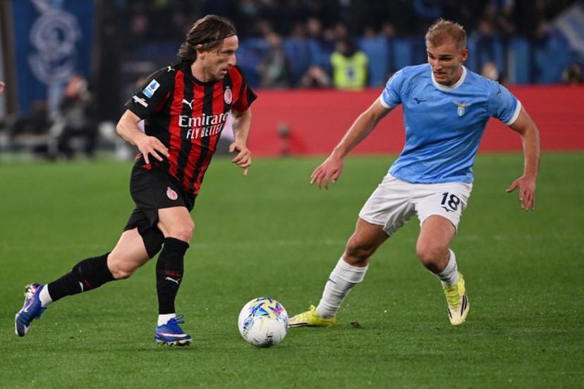 AC Milan's Croatian midfielder #14 Luka Modric runs with the ball in front of Lazio's Danish forward #18 Gustav Isaksen (R) during the Italian Serie A football match between Lazio and AC Milan at the Olympic Stadium in Rome on March 15, 2026. Alberto PIZZOLI / AFP