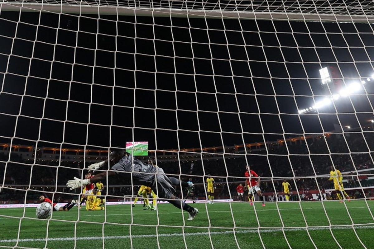 Egypt's forward #10 Mohamed Salah scores past Zimbabwe's goalkeeper #22 Washington Arubi during the Africa Cup of Nations (CAN) group B football match between Egypt and Zimbabwe at Adrar Stadium in Agadir on December 22, 2025. FRANCK FIFE / AFP