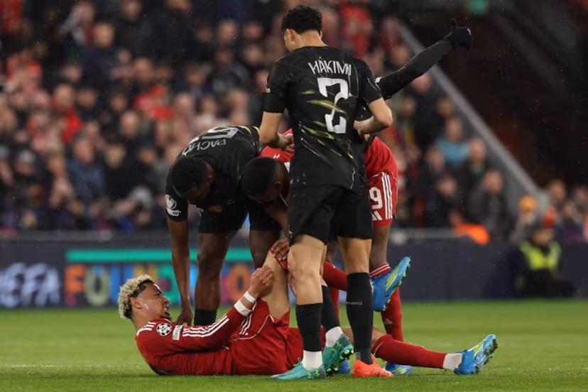 Players care for Liverpool's French striker #22 Hugo Ekitike who lies injured during the UEFA Champions League quarter final, second-leg football match between Liverpool and Paris Saint-Germain at Anfield in Liverpool, north west England on April 14, 2026. FRANCK FIFE / AFP