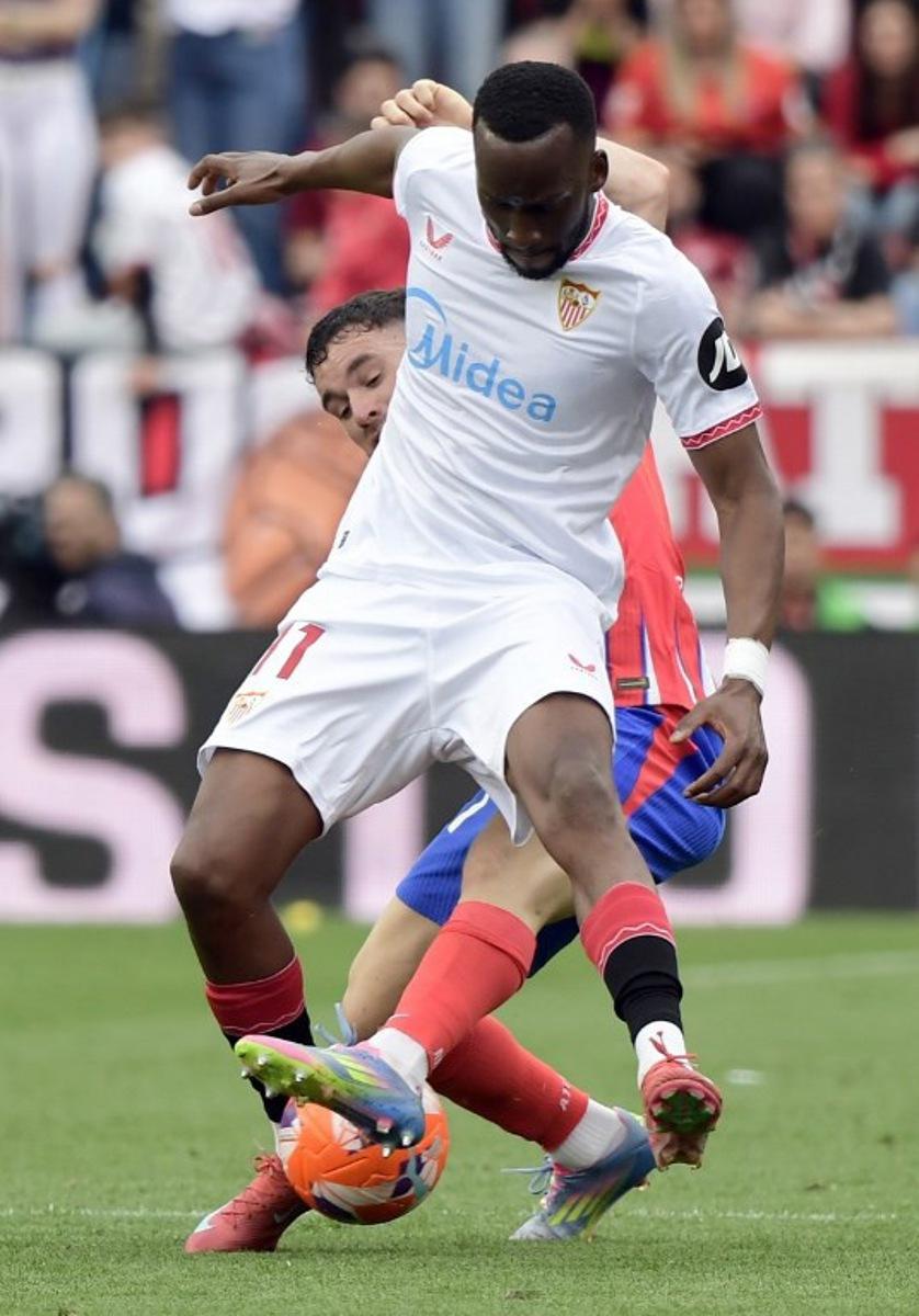 Atletico Madrid's Spanish defender #21 Javi Galan (BACK) and Sevilla's Belgian forward #11 Dodi Lukebakio fight for the ball during the Spanish league football match between Sevilla FC and Club Atletico de Madrid at the Ramon Sanchez Pizjuan stadium in Seville on April 6, 2025. CRISTINA QUICLER / AFP