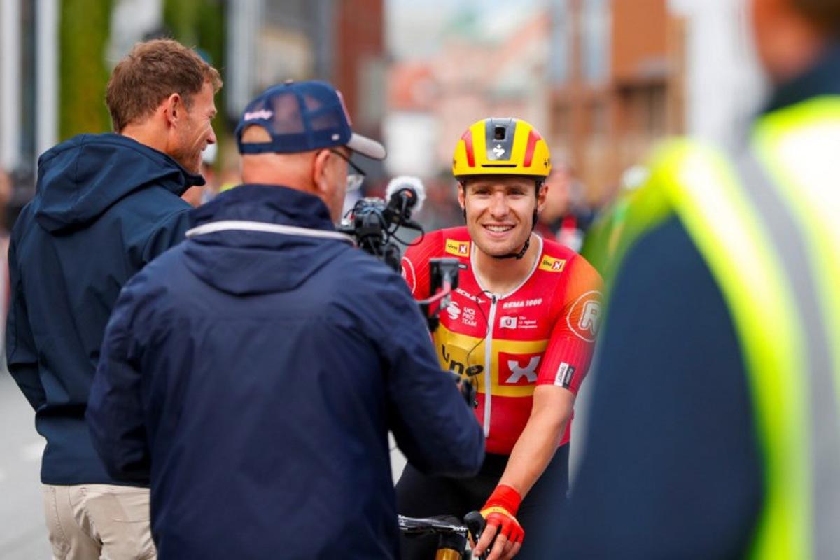Uno-X Pro Cycling Team's Norwegian rider Fredrik Dversnes (R) reacts and is welcomed by Uno-X Mobility's CEO Thor Hushovd (L) after winning the fourth and final stage of the Arctic Cyling Race 2025 in Tromso, Norway, on August 10, 2025. Rune Stoltz Bertinussen / NTB / AFP