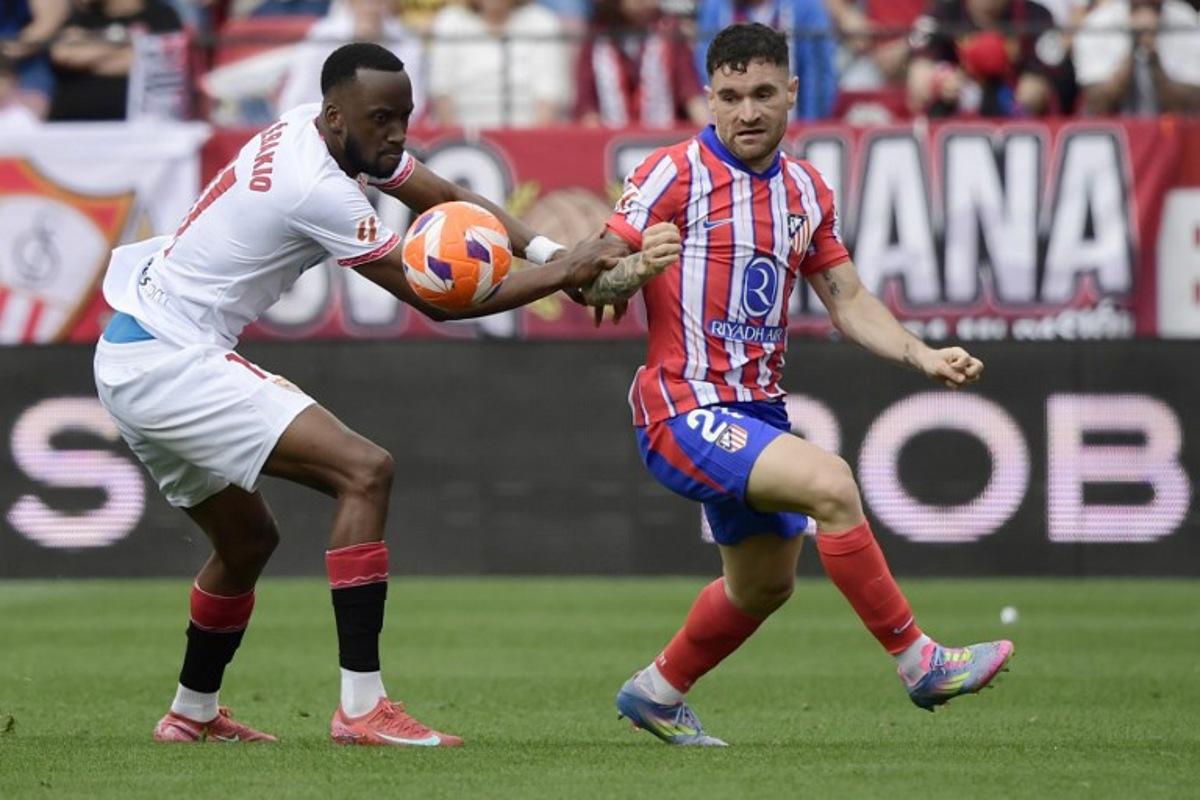 Sevilla's Belgian forward #11 Dodi Lukebakio (L) and Atletico Madrid's Spanish defender #21 Javi Galan fight for the ball during the Spanish league football match between Sevilla FC and Club Atletico de Madrid at the Ramon Sanchez Pizjuan stadium in Seville on April 6, 2025. CRISTINA QUICLER / AFP