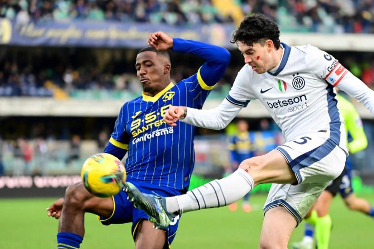 Inter Milan's Italian defender #95 Alessandro Bastoni shoots past Hellas Verona's Belgian midfielder #38 Jackson Tchatchoua during the Italian Serie A football match between Hellas Verona and Inter Milan at Marcantonio Bentegodi Stadium, in Verona on November 23, 2024. This weekend, players in Serie A are sporting a red mark on their cheeks as part of a campaign challenging violence against women, participating in the campaign Un Rosso Alla Violenza - A red card to violence. Piero CRUCIATTI / AFP