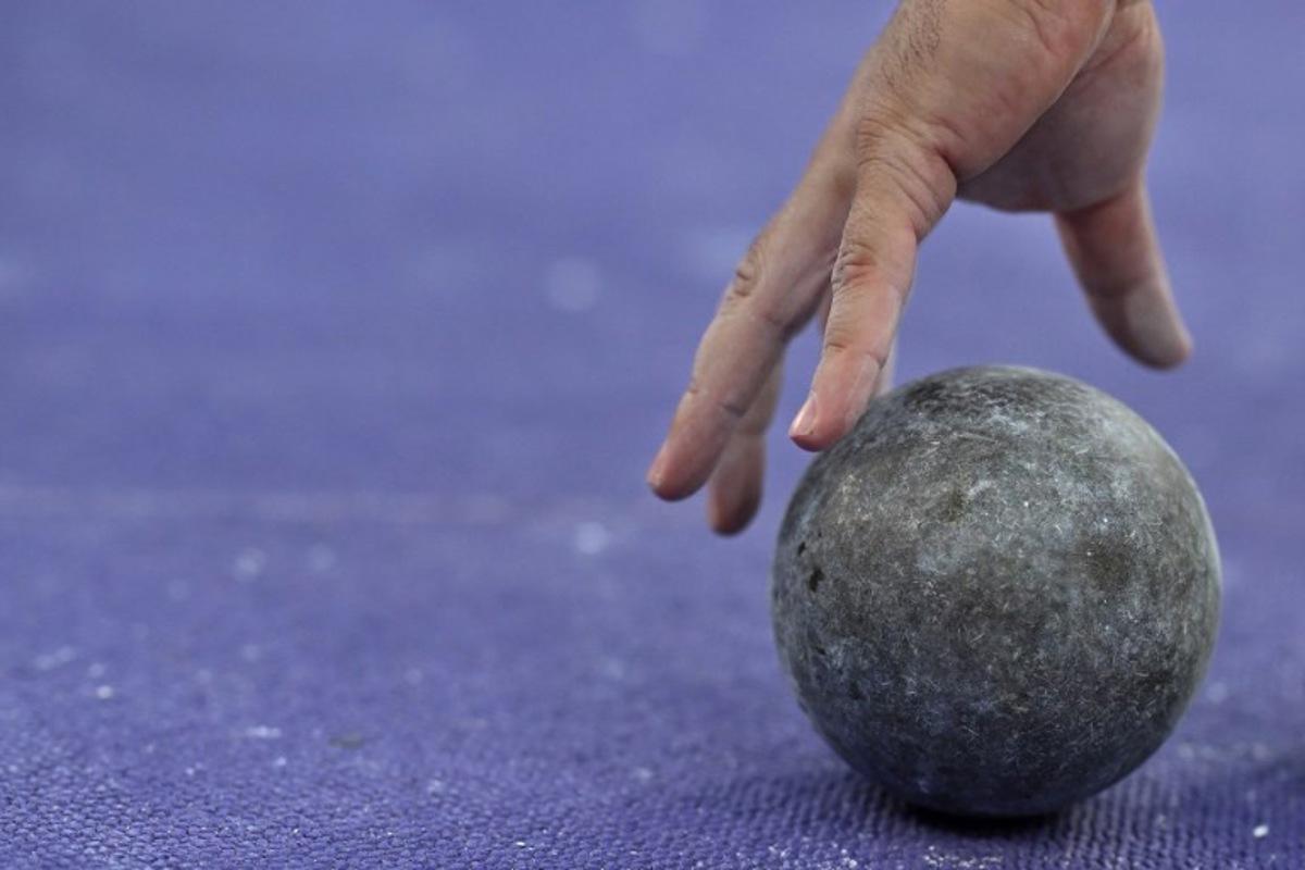 Romania's Andrei Rares Toader picks up his shot put to compete in the men's shot put qualification of the athletics event at the Paris 2024 Olympic Games at Stade de France in Saint-Denis, north of Paris, on August 2, 2024. Ben STANSALL / AFP