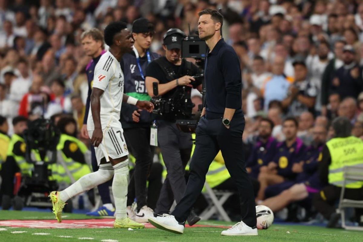 Real Madrid's Brazilian forward #07 Vinicius Junior walks past Real Madrid's Spanish coach Xabi Alonso as he is substituted during the Spanish league football match between Real Madrid CF and FC Barcelona at Santiago Bernabeu Stadium in Madrid on October 26 , 2025. Oscar DEL POZO / AFP
