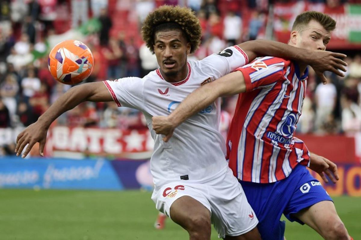 Sevilla's French defender #22 Loic Bade and Atletico Madrid's Norwegian forward #09 Alexander Sorloth fight for the ball during the Spanish league football match between Sevilla FC and Club Atletico de Madrid at the Ramon Sanchez Pizjuan stadium in Seville on April 6, 2025. CRISTINA QUICLER / AFP